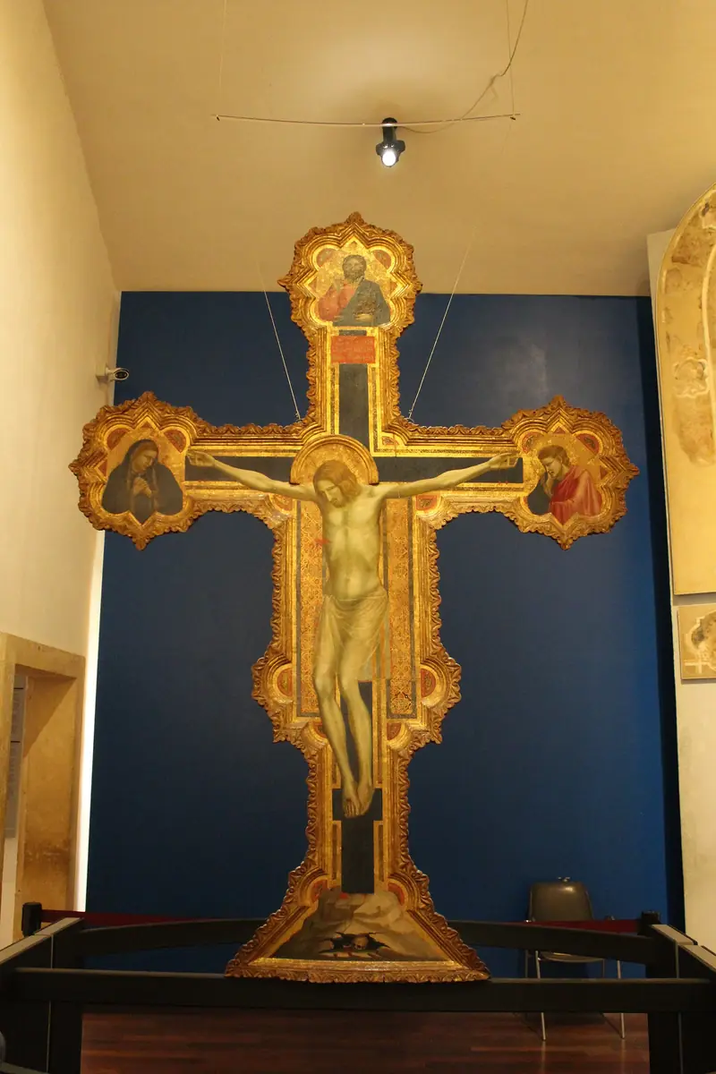 Giotto's painted Crucifix displayed on a blue wall in the Musei Civici Eremitani in Padua