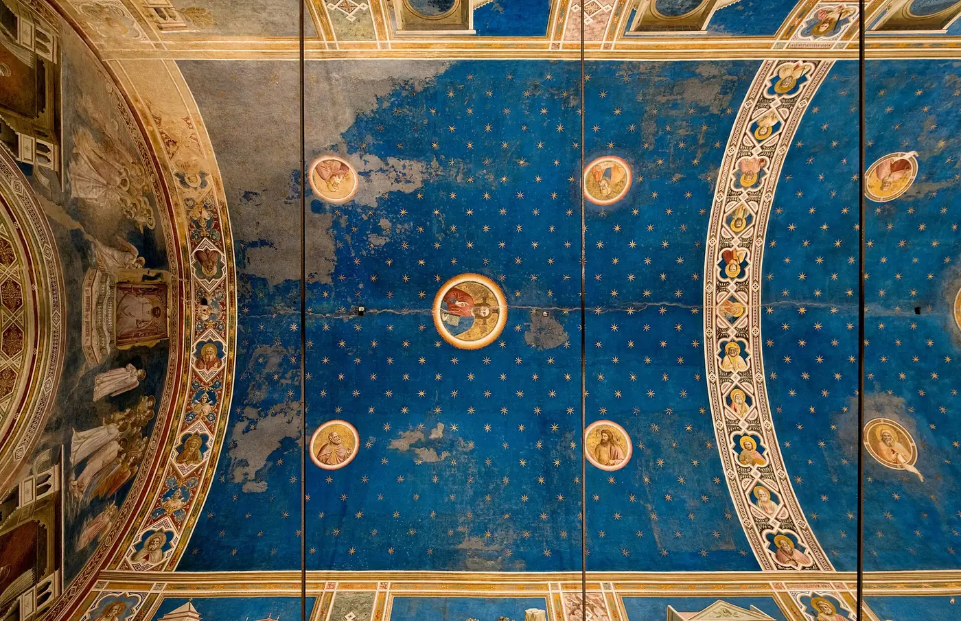 Giotto's barrel vault in the Scrovegni Chapel, deep blue with gold eight-pointed stars and painted roundels of Christ, the Madonna and prophets