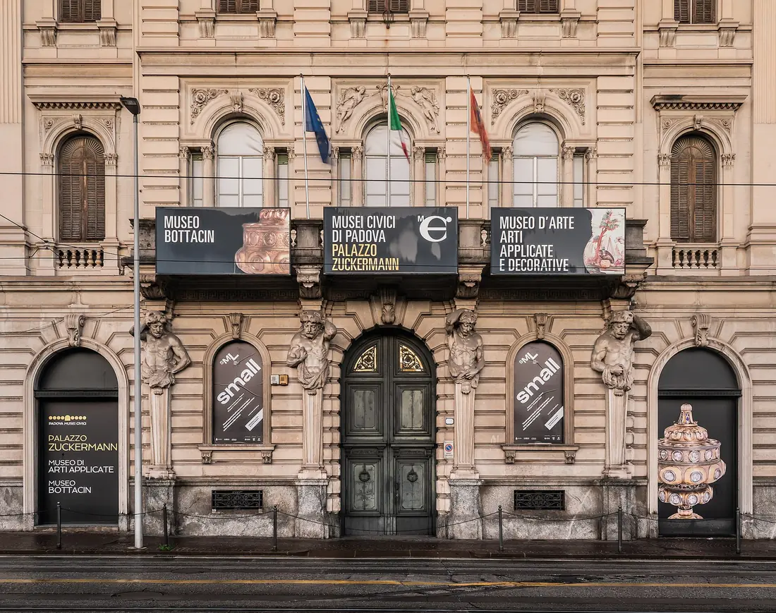 The ornate facade of Palazzo Zuckermann on Corso Garibaldi in Padua, with museum banners above the doors
